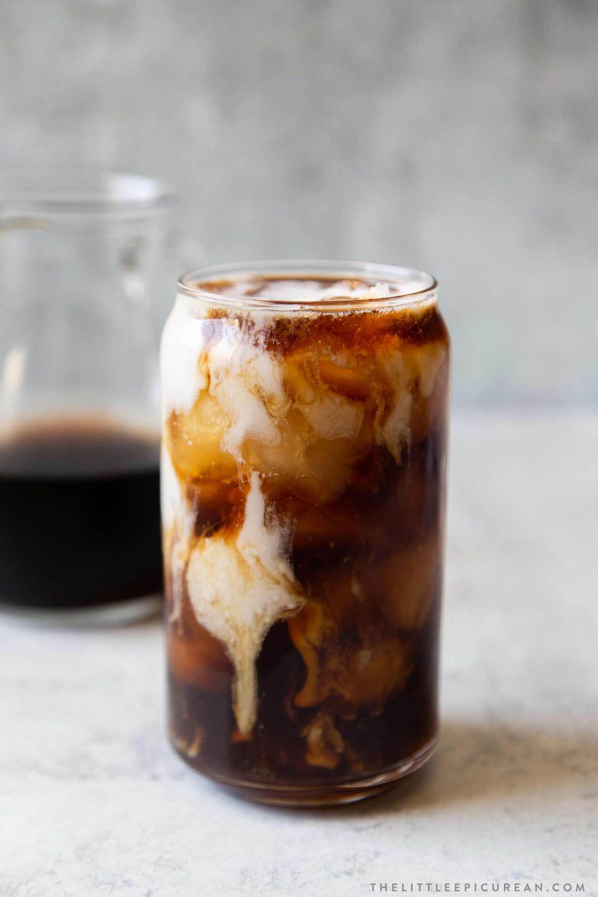 A glass of cold brew coffee with cream swirling through it